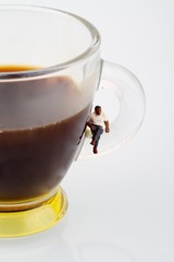 miniatura di uomo seduto su tazza di caffè