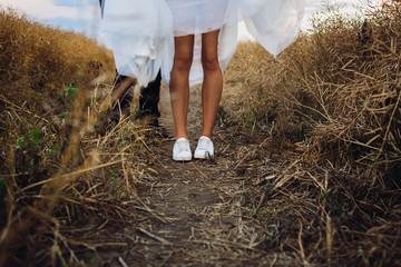 beautiful legs of the bride in white sneakers
