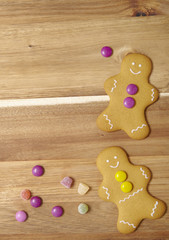 Hand decorated gingerbread men on a kitchen counter background with candy and empty space at side