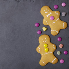 Hand decorated gingerbread men on a rustic slate background, with candy and blank space at side
