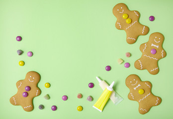 Hand decorated gingerbread men on a pastel green background, with candy and icing tubes forming a page border