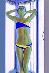 Slim woman in solarium getting sun tan