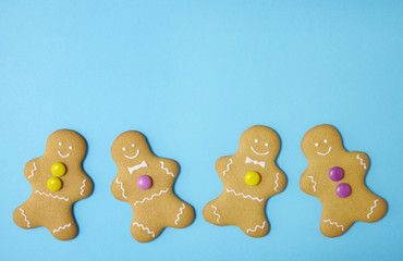 A line of hand decorated gingerbread men on a bright blue background with empty space above