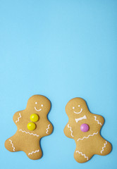 Hand decorated gingerbread men on a bright blue background with empty space above