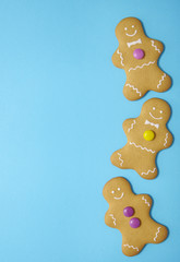 Hand decorated gingerbread men on a bright blue background with blank space at side
