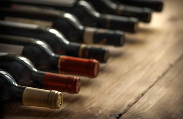Row of wine bottles with  red  wine on wooden desk. Low depth of field. 