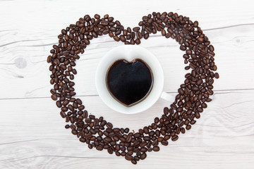 coffee on heart shape ceramic mug cup and coffee beans which are arranged as heart symbol