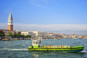 Gruener Lastenkahn vor der Kulisse des Markusplatz in Venedig