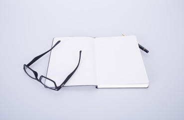 notebook with glasses and pen on the blackground.