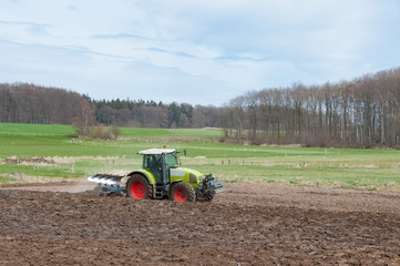 Fototapeta premium Traktor auf dem Feld mit Pflug