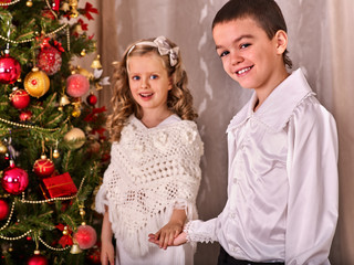 Children receiving gifts under Christmas tree. Black and white retro. Brother and sister home alone in Christmas evening.