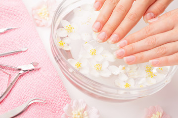 Beautiful woman's hands with manicure in bowl of water