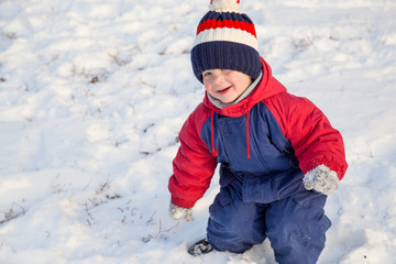 Fototapeta na wymiar Funny little boy walking on snow