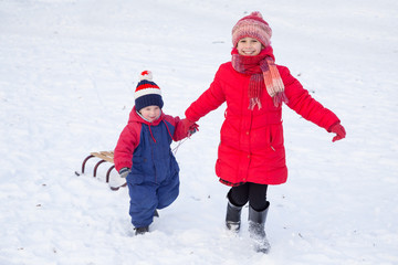 Two happy kids with sled walking on snow