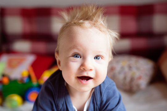 Little Baby Boy With Spiky Hair Crawling On Bed.