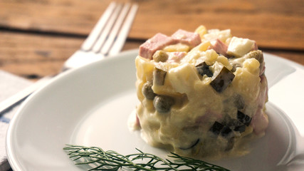 Russian traditional salad Olivier, on wooden background