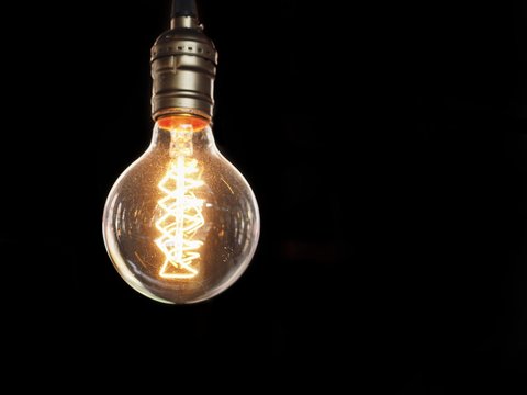 Isolated glowing modern light bulb on black background