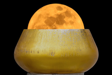Super moon yellow in alms bowl on a black background.