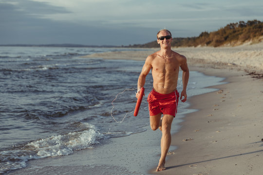 lifeguard on the beach with glasses, with a life buoy, wet sand and sea at sunset