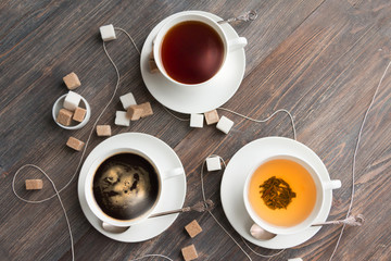 Tea, black tea, green tea, black espresso coffee in white porcelain cups on rustic wooden table. Top view.