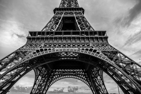 Black-white photo of close-up element part of Eiffel tower in Paris against dramatic twilight sky at evening summer time.
