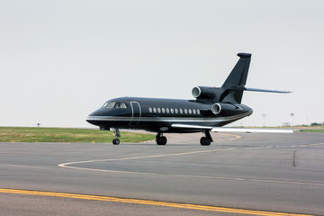 Black business jet taxiing from the runway