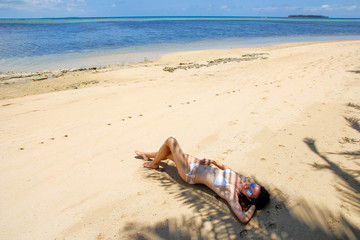 Fototapeta na wymiar Young woman in bikini lying on the beach on Makaha'a island near