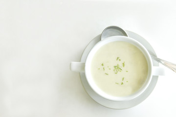 Cream soup in white cup on white table background with space for text here