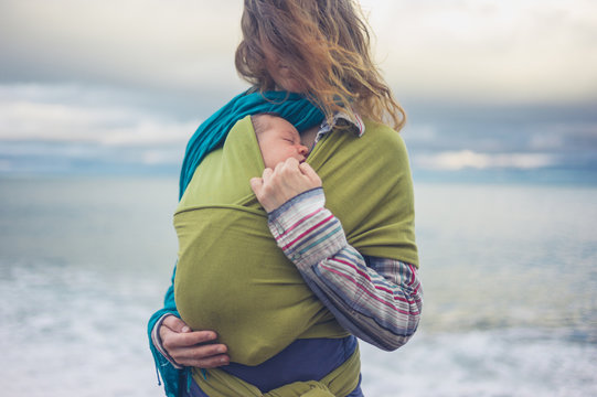 Mother with baby in sling by the sea