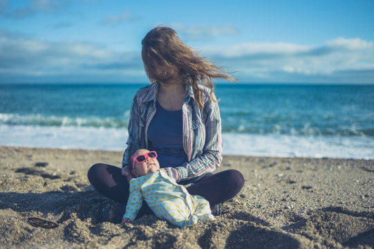 Baby wearing sunglasses on the beach with his mother