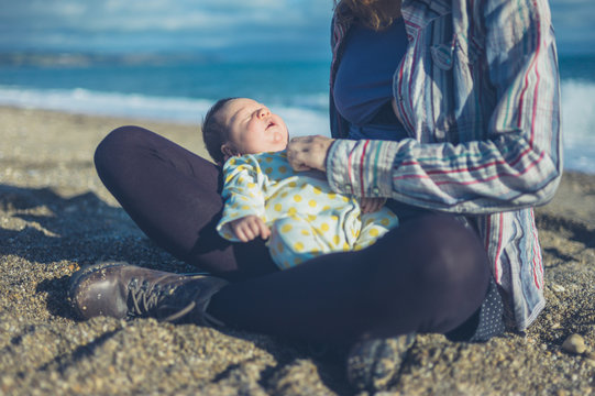 Mother sitting on beach with baby