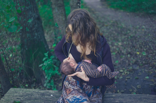Woman breastfeeding baby in the forest