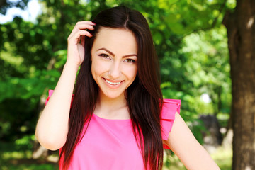 Young beautiful woman in pink dress standing in the park