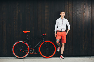 Hipster with bycicle and tatoo at dark background