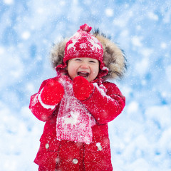 Baby playing with snow in winter.