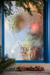 Christmas colorful blur. Christmas tree ornaments and boxes with presents as seen through window with ice
