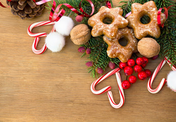 Christmas decoration with gingerbreads, branch of spruce, candies, berry and walnuts on wooden table