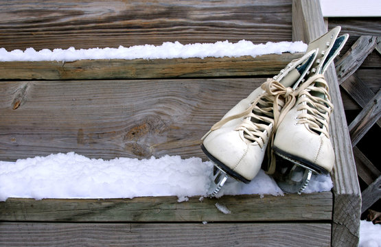 Ice Skates and Snow – A pair of white ice skates on steps covered with snow.