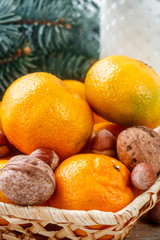 Tangerines and nuts in a wicker basket on the background of fir