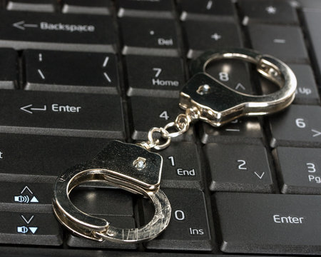 Handcuffs Lying On Laptop Keypad