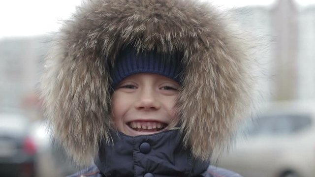 Portrait of a boy in winter jacket with hood on his head