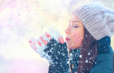 Beauty winter girl blowing snow in frosty winter park
