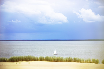White Sailboat On The Background Of Dunes And Blue Sky