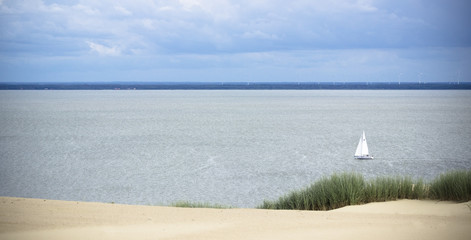 White Sailboat On The Background Of Dunes And Blue Sky