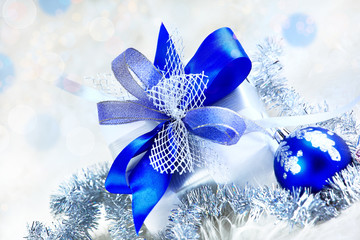 Christmas. holiday gift in a beautiful package and  a blue glass bowl with ornament on festive background