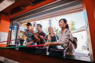 Multiracial friends playing arcade game at amusement park