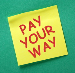 The phrase Pay Your Way in red text on a yellow sticky note as a reminder to earn enough to cover your expenses and live within your means