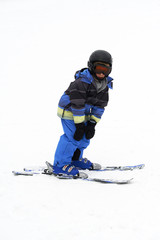 Child boy skiing in mountains. Active teenager kid with safety helmet and goggles. Ski race for young children. Winter sport for family. Kids ski lesson in alpine school. Young skier racing in snow