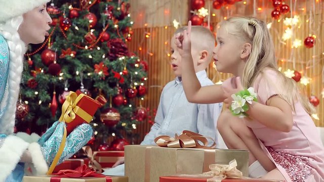 The boy and the girl choose Christmas gifts and assistant of Santa Claus.