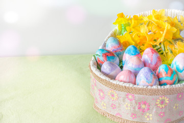 Basket of Hand Painted Easter Eggs with Daffodils on Table Horizontal with Copy Space Left & Bokeh